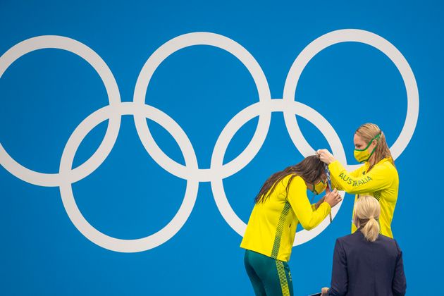競泳女子200m背泳ぎの表彰式で、同じオーストラリア代表で銅メダルのエミリー・シーボム選手（右）から金メダルをかけてもらうケーリー・マキオン選手。