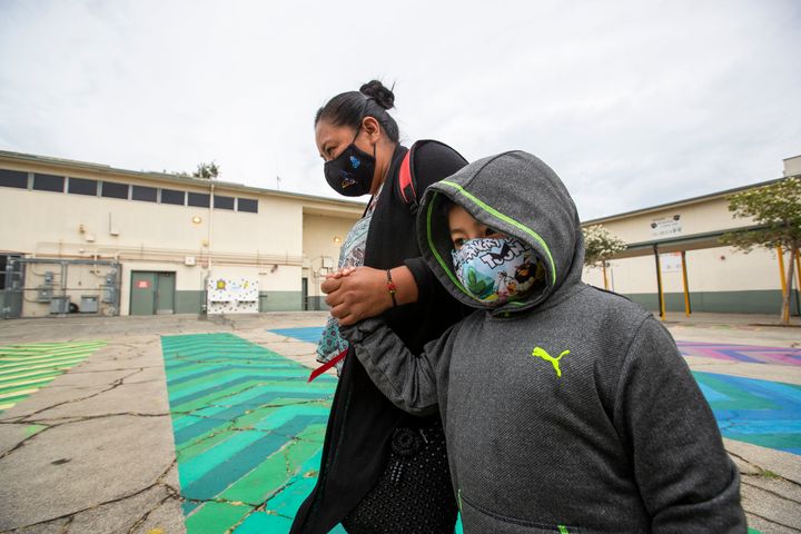 First grade student Daniel Cano, 5, and his mom, Sonia Cano, walk past COVID-19 safety precaution signs at Euclid Avenue Elementary School Monday, July 26, 2021 in Los Angeles.