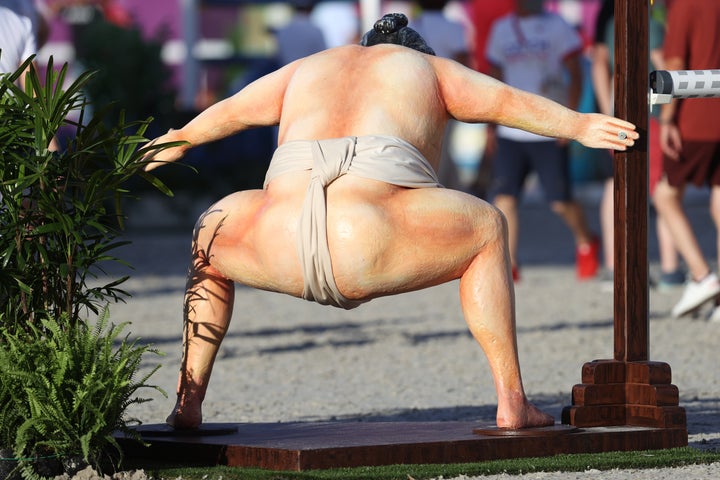 A rear view of the sumo wrestler during the equestrian jumping.