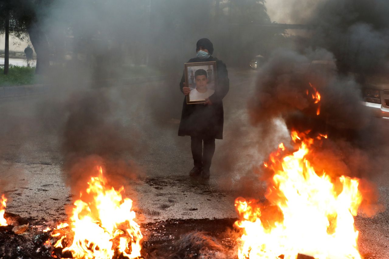 A woman holds a picture of one of the blast's victims during a protest earlier this year