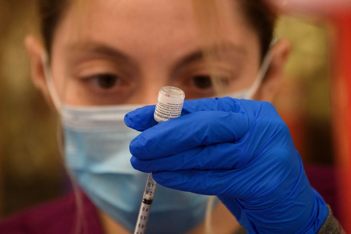 A health care worker prepares a dose of the Pfizer COVID-19 vaccine. The vaccine was the first to achieve full authorization 