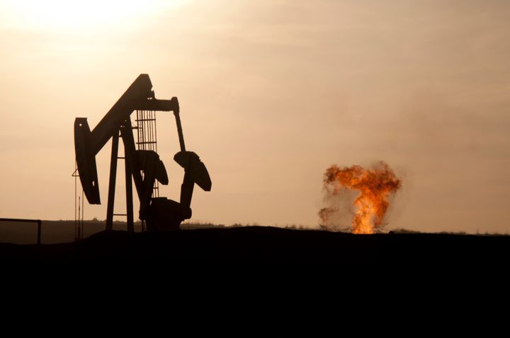 An oil well jack pump and a natural gas flare-off at sunset in the Bakken oil field north of Williston, North Dakota.