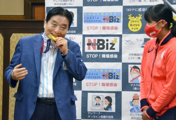 Nagoya city Mayor Takashi Kawamura bites the Olympic gold medal of softball pitcher Miu Goto during a ceremony in Nagoya on A