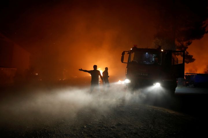 Φλόγες ξεπηδούν δίπλα σε όχημα της Πυροσβεστικής καθώς η πυρκαγιά μαίνεται στο χωριό Ροβιές της Εύβοιας. 4 Αυγούστου 2021. REUTERS/Costas Baltas
