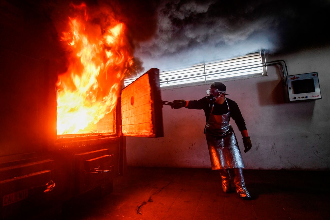 Cremating a single corpse usually takes between two and three hours and releases almost 600 pounds of carbon dioxide. In this January 2021 photo, a crematorium employee in Mexico closes a cremation oven during the cremation of a COVID-19 victim.