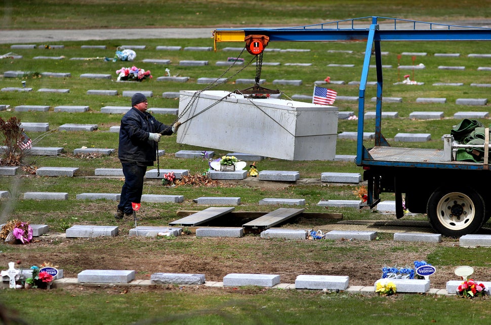 A worker lowers a concrete burial vault into a new grave at Mt. Hope Cemetery in Boston on April 22, 2020. 