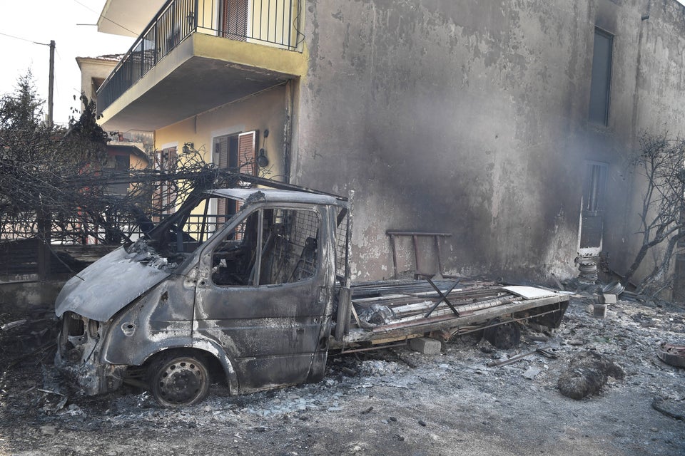 The remains of a van sits amongst burned trees and rubble as Greece swelters in a record-breaking