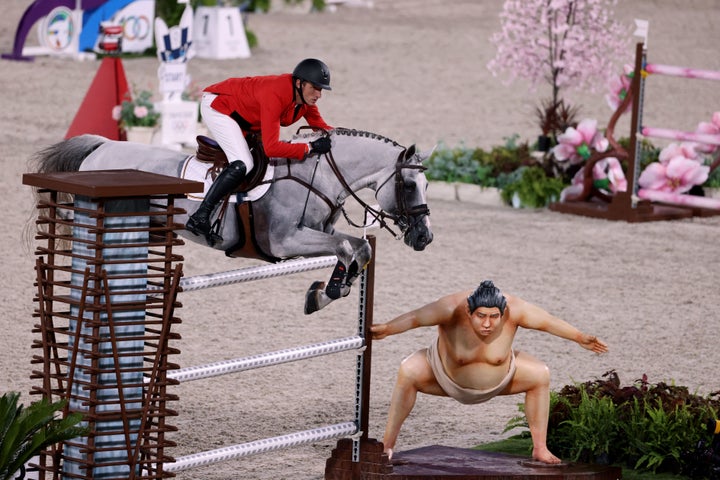 Belgium's Gregory Wathelet jumps past the sumo statue. 