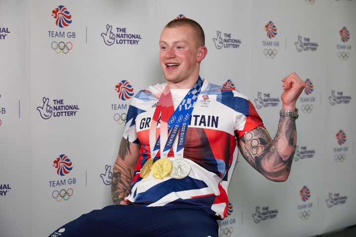 Adam Peaty being interviewed back in London with his three Tokyo medals.
