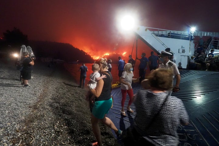 People embark a ferry during an evacuation from Kochyli beach as wildfire approaches near Limni village on the island of Evia, about 160 kilometers (100 miles) north of Athens, Greece, Friday, Aug. 6, 2021. 