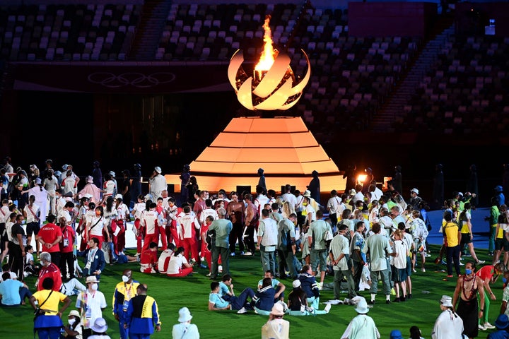 Athletes celebrate next to the Olympic Cauldron at the closing ceremony of the Tokyo Olympics.