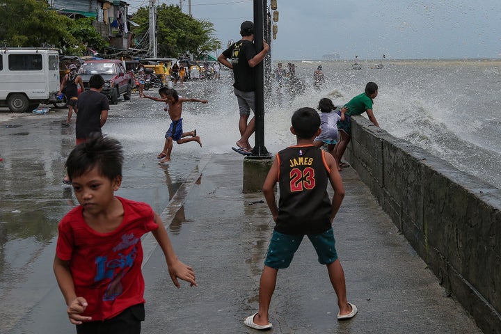 Children play in floodwater near the shore of the polluted Manila Bay in the Tondo district of Manila City in the Philippines