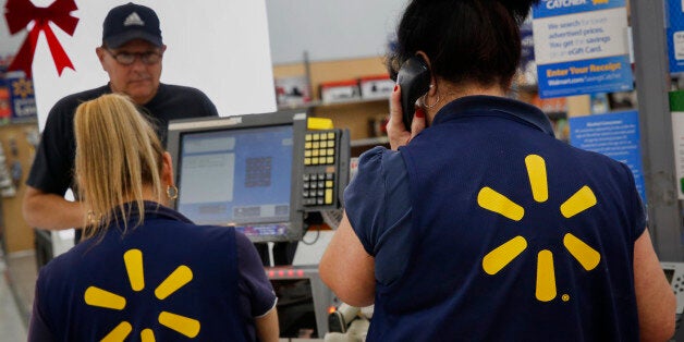 Employees assist shoppers at the check out counter of a Wal-Mart Stores Inc. location ahead of Black Friday in Los Angeles, California, U.S., on Monday, November 24, 2014. Retailers are planning to open earlier on Thanksgiving day this year in a bid to draw shoppers. Wal-Mart Stores Inc. is making Black Friday, the shopping day after Thanksgiving, a weeklong event this year. Photographer: Patrick T. Fallon/Bloomberg via Getty Images