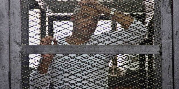 Canadian-Egyptian acting Al-Jazeera bureau chief Mohammed Fahmy appears in a defendant's cage in a courthouse near Tora prison along with other defendants during a trial on terror charges in Cairo, Egypt, Saturday, May 3, 2014. Fahmy made a rare appeal to the judge from outside of the defendants' cage, at the end of which the judge wished him a "happy" World Press Freedom Day. In his brief plea Saturday, Fahmy stood directly before the judge's bench. Fahmy said journalists have to speak to all sides to do their jobs. (AP Photo/Hamada Elrasam)