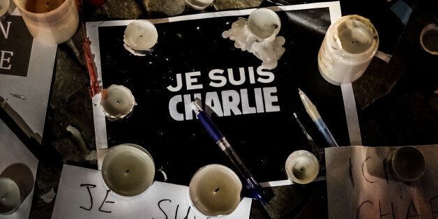 BERLIN, GERMANY - JANUARY 08: Papers with 'I am Charlie' displayed are left near candles at a vigil in front of the French Embassy following the terrorist attack in Paris on January 7, 2015 in Berlin, Germany. Twelve people were killed including two police officers as two gunmen opened fire at the offices of the French satirical publication Charlie Hebdo. (Photo by Carsten Koall/Getty Images)