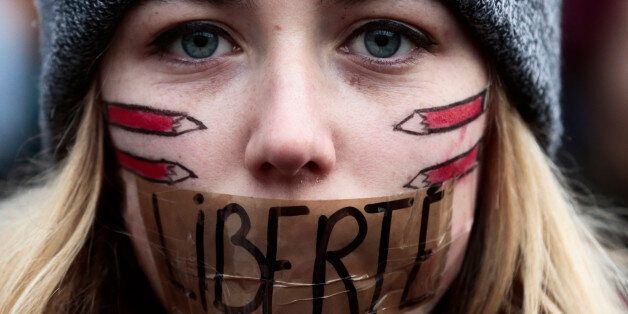 A woman has taped her mouth displaying the word Freedom on the tape, as she gathers with several thousand people in solidarity with victims of two terrorist attacks in Paris, one at the office of weekly newspaper Charlie Hebdo and another at a kosher market, front of the Brandenburg Gate near the French embassy in Berlin, Sunday, Jan. 11, 2015. in Berlin, Sunday, Jan. 11, 2015. (AP Photo/Markus Schreiber)