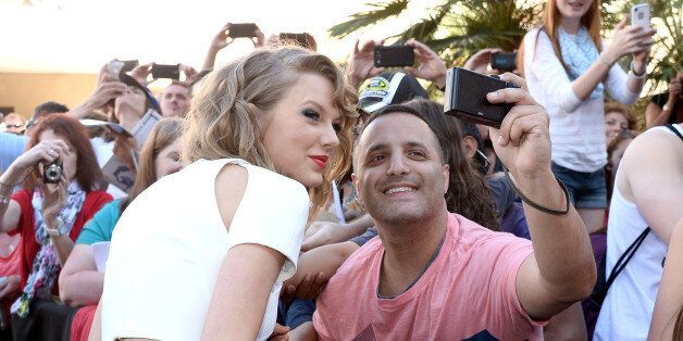 LAS VEGAS, NV - APRIL 06: Recording artist Taylor Swift takes a selfie photo with fans during the red carpet at the 49th Annual Academy of Country Music Awards at the MGM Grand Garden Arena on April 6, 2014 in Las Vegas, Nevada. (Photo by Frazer Harrison/ACMA2014/Getty Images for ACM)