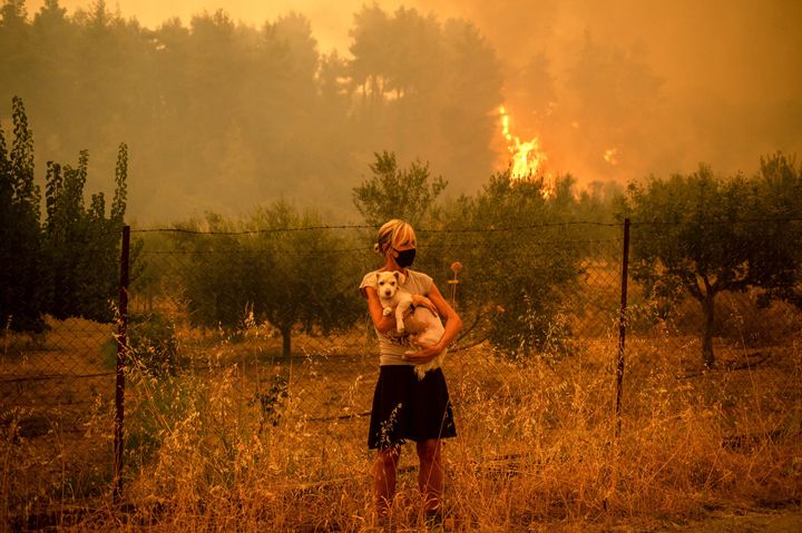 Una mujer con su perro, entre los incendios en la isla de Eubea (Grecia) este 8 de agosto. 