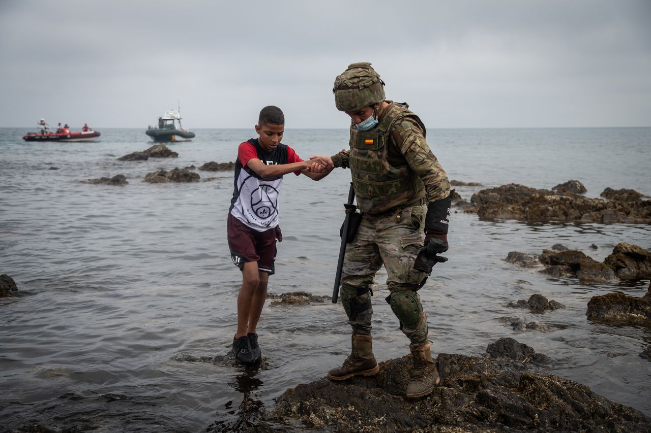 A Spanish soldier helps a migrant after he crossed the border between Morocco and Spain by swimming in May, 2021