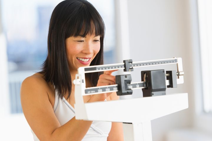 USA, New Jersey, Jersey City, Smiling woman checking her weight