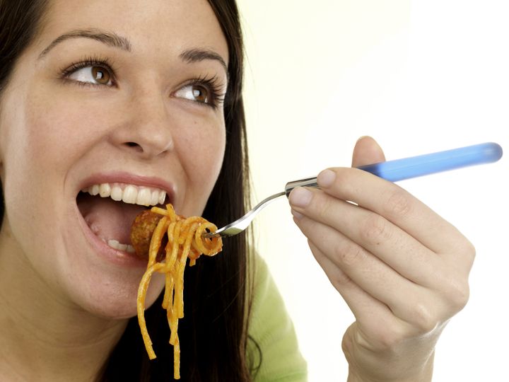 young woman eating spaghetti...