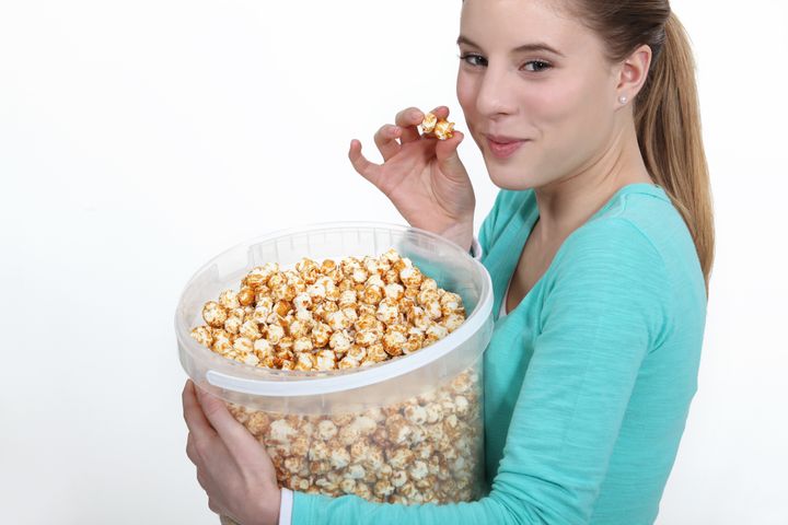woman eating popcorn from large ...