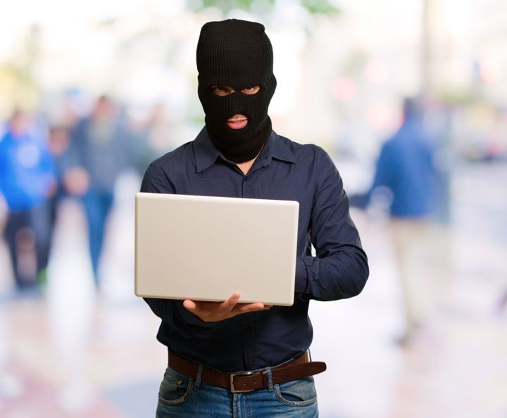 young male thief holding laptop ...