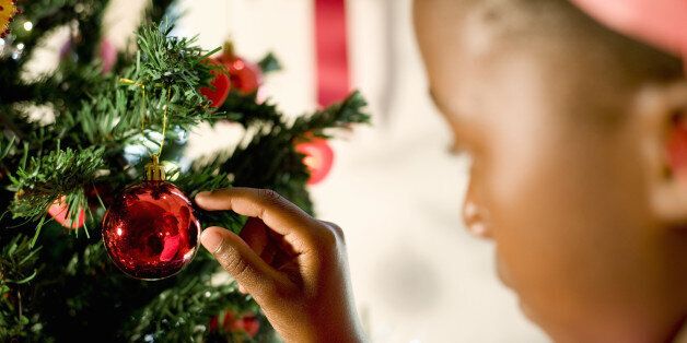 A young girl places a Christmas decoration onto the Christmas tree, Johannesburg, Gauteng Province, South Africa