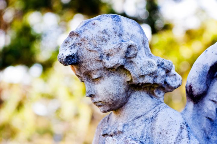 Closeup old staue of little angel from cemetery