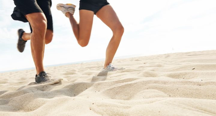 Cropped shot of the legs of two athletes running on a beach