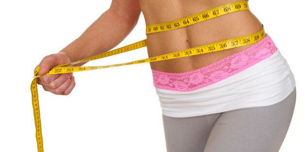 close up of fit waist measuring weight loss isolated on white background