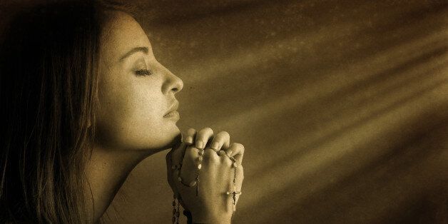 Praying young woman in divine light