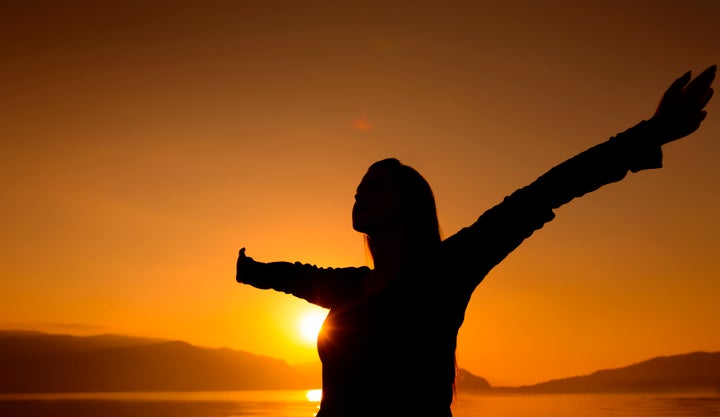 woman silhouette with arms raised, sunset shoot.