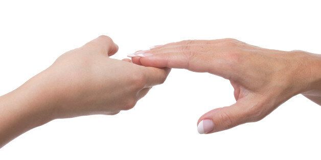 Hand of a mature woman takes the hand of a younger woman, isolated on white