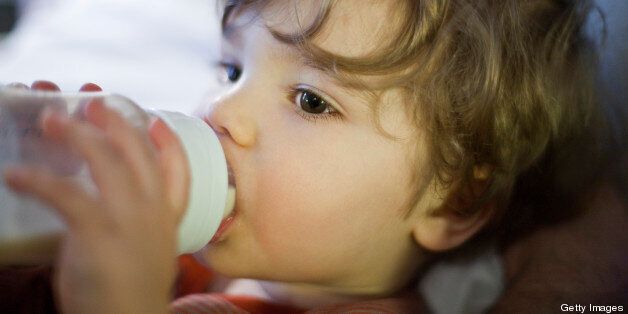 Toddler boy drinking milk from baby bottle