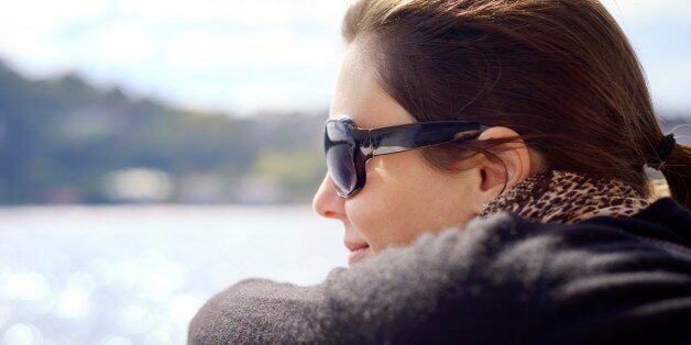 A beautiful, happy, mid-adult woman leans on the boat's railing and looks out over the water. Taken on the Bosphorus, Istanbul, Turkey.