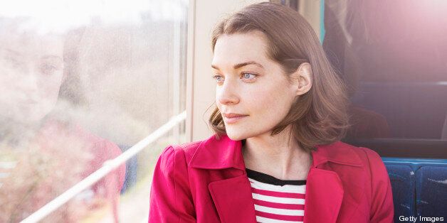 Woman sitting in train looking out of window.