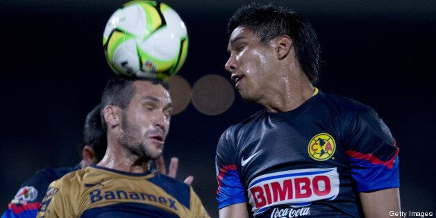 America's Juan Carlos Valenzuela (R) vies for the ball with Pumas's Luis Garcia (L) during their Clausura 2013 Mexican league football quarter final match at the Olimpico stadium on May 8, 2013 in Mexico City. AFP PHOTO/Yuri CORTEZ (Photo credit should read YURI CORTEZ/AFP/Getty Images)