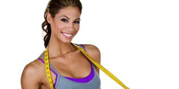 Cute hispanic woman wearing fitness clothing and holding a measuring tape 
