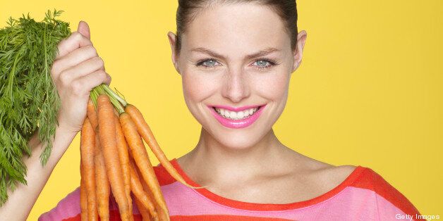 young woman holding bunch of carrots