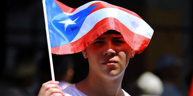 UNITED STATES - JUNE 08: Jose Roman, 16, of Puerto Rico shades himself with a Puerto RIcan flag in order to stay cool. Some 2 million spectators braved the hot, muggy weather at the 2008 51st Annual Puerto Rican Day Parade along Fifth Avenue (Photo by Robert Sabo/NY Daily News Archive via Getty Images)