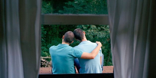Two men embracing on rooftop, rear view