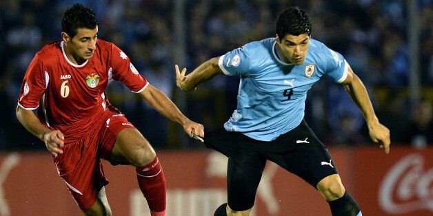 Jordan's footballer Tareq Khattab (L) vies for the ball with Uruguay's forward Luis Suarez, during their Brazil 2014 FIFA World Cup intercontinental playoff second leg football match, on November 20, 2013, at the Centenario stadium in Montevideo. AFP PHOTO / PABLO PORCIUNCULA (Photo credit should read PABLO PORCIUNCULA/AFP/Getty Images)