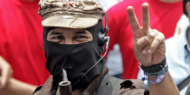 The leader of the Zapatista National Libertation Army (EZLN), Sub Comandante Marcos (C), flashes the 'v' sign as he takes part in a march along the streets of the Mexico City, 01 May, 2006 during the celebrations for May Day. From rural mountainous Nepal to the industrial heartland of Germany, workers took to the streets around the world on Monday in largely peaceful May Day demonstrations for labour rights, as immigrants in the United States prepared a jobs boycott. AFP PHOTO / Luis ACOSTA (Photo credit should read LUIS ACOSTA/AFP/Getty Images)