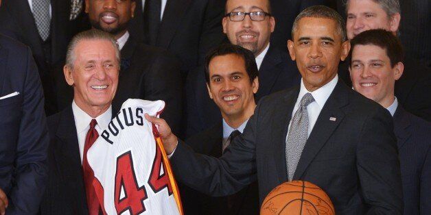 US President Barack Obama holds a jersey and basketball presented to him by members of the Miami Heat during an event honoring the 2013 NBA champions in the East Room of the White House in Washington on January 14, 2014. From left: Miami Heat president Pat Riley and head coach Erik Spoelstra. AFP PHOTO/Mandel NGAN (Photo credit should read MANDEL NGAN/AFP/Getty Images)
