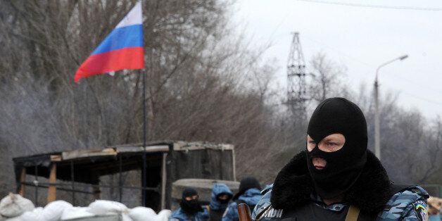 Armed masked men who call themselves members of Ukraine's disbanded elite Berkut riot police force stand at their checkpoint under a Russian flag on a highway that connect Black Sea Crimea peninsula to mainland Ukraine near the city of Armyansk, on February 28, 2014. The spiralling tensions in a nation torn between the West and Russia took today a severe new turn when Ukraine's interim president Oleksandr Turchynov accused Russian soldiers and local pro-Kremlin militia of staging raids on Crimea's main airport and another base on the southwest of the peninsula where pro-Moscow sentiments run high. AFP PHOTO / VIKTOR DRACHEV (Photo credit should read VIKTOR DRACHEV/AFP/Getty Images)