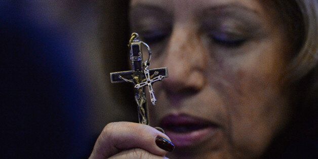 A woman holds a cross outside the National Shrine of Our Lady of Aparecida during a mass celebrated by Pope Francis on July 24, 2013 in Aparecida, Brazil. Pope Francis warned Catholics on Wednesday against 'ephemeral idols' like money at his first public mass in his native Latin America as huge crowds lined the streets to cheer him. The first Latin American and Jesuit pontiff visited Aparecida to lead his first big mass since arriving in the country for a week-long visit of which highlight is the huge five-day Catholic gathering World Youth Day. AFP PHOTO / POOL - LUCA ZENNARO (Photo credit should read LUCA ZENNARO/AFP/Getty Images)