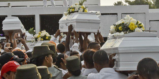 The coffins with the remains of the 33 schoolchildren killed in a bus fire are taken for burial at the cemetery in Fundacion, Colombia, on May 28, 2014. Colombians expressed horror after 33 children burnt to death when an overcrowded bus burst into flames and the driver fled the scene, pursued by a mob that stoned his house. According to a witness, the bus went up in flames as the driver, who lost two of his own children in the tragedy, refuelled it with a jerry can. The children, aged between three and 12 years old, were returning from evangelical church services in the small northern town of Fundacion. (Photo credit should read LUIS ACOSTA/AFP/Getty Images)