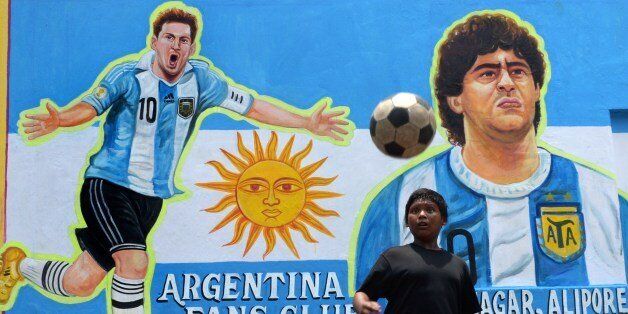 An Indian boy heads a football in front of graffiti of Argentine soccer player Lionel Messi at the roadside in Kolkata on June 10, 2014. Football fans in the eastern Indian city are gearing up for the upcoming Brazil FIFA World Cup 2014 and decorating their clubs with football-related paraphernalia. AFP PHOTO/ Dibyangshu Sarkar (Photo credit should read DIBYANGSHU SARKAR/AFP/Getty Images)
