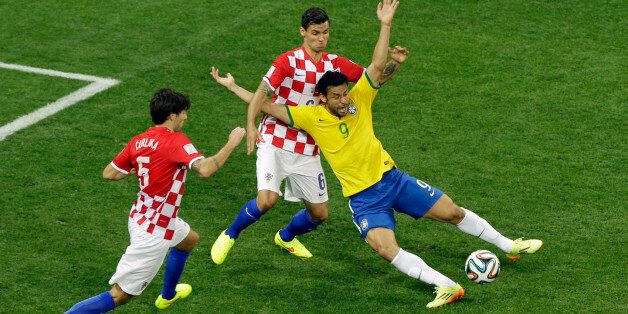 Brazil's Fred, right, falls after making contact with Croatia's Dejan Lovren during the group A World Cup soccer match between Brazil and Croatia, the opening game of the tournament, in the Itaquerao Stadium in Sao Paulo, Brazil, Thursday, June 12, 2014. At left is Croatia's Vedran Corluka. (AP Photo/Thanassis Stavrakis)